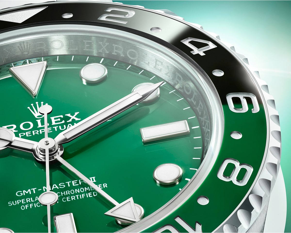 Close-up of watch with green dial showing GMT-Master II model, featuring black and white numbered rotating bezel, white triangular and rectangular hour markers, and silver hands displaying approximately 10:10 time.