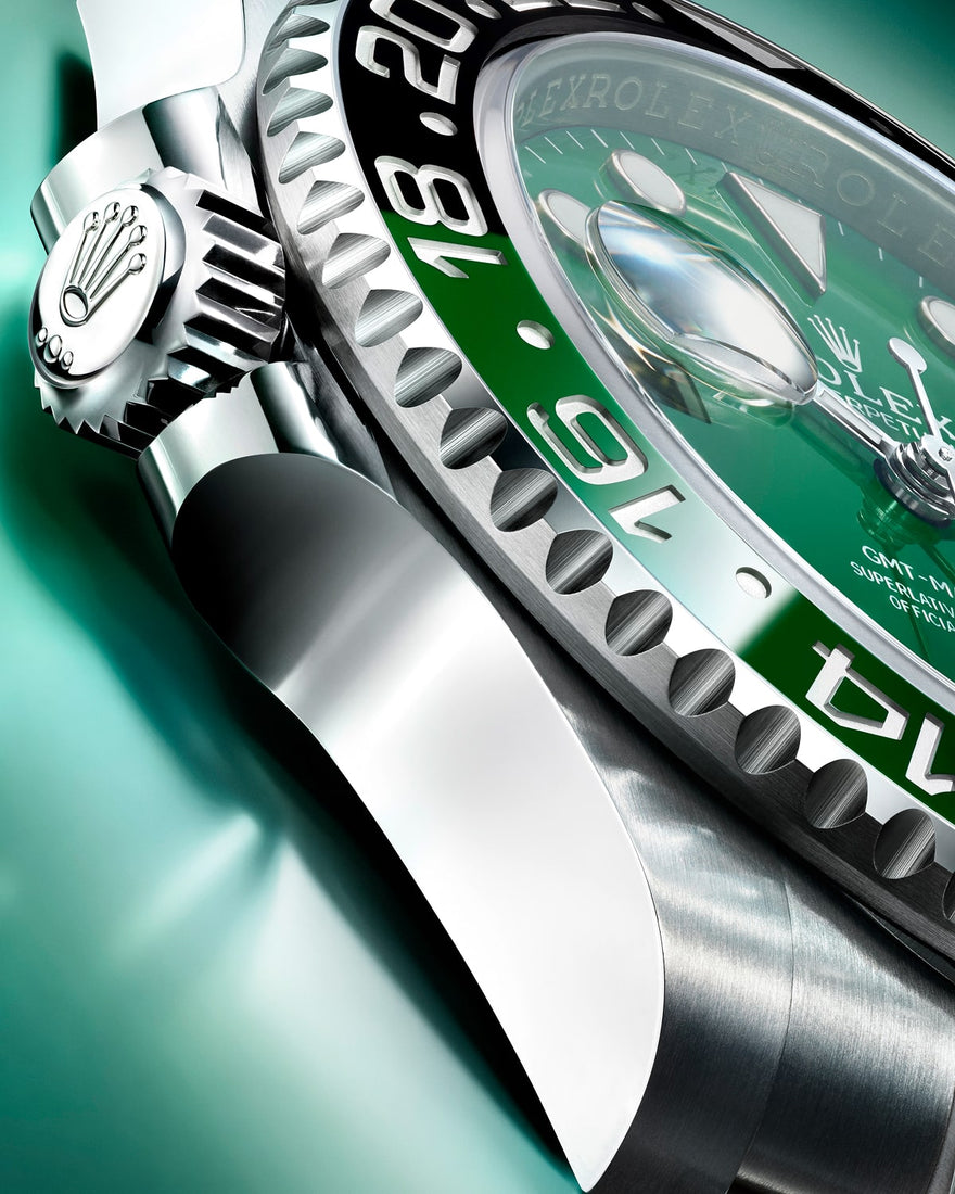 Macro detail of luxury diving watch showing fluted crown, green unidirectional rotating bezel with white numerals, green dial with date magnification window, and brushed stainless steel case construction.