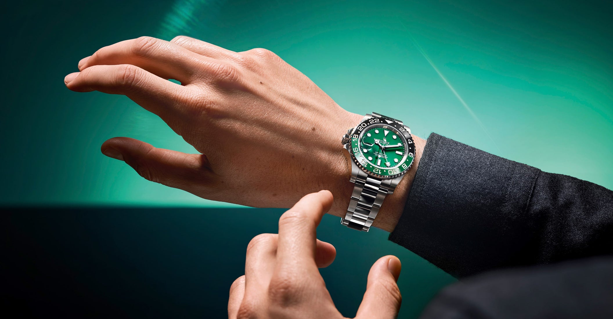 Macro detail of diving watch showing fluted crown, green unidirectional rotating bezel with white numerals, green dial with date magnification window, and brushed stainless steel case construction.