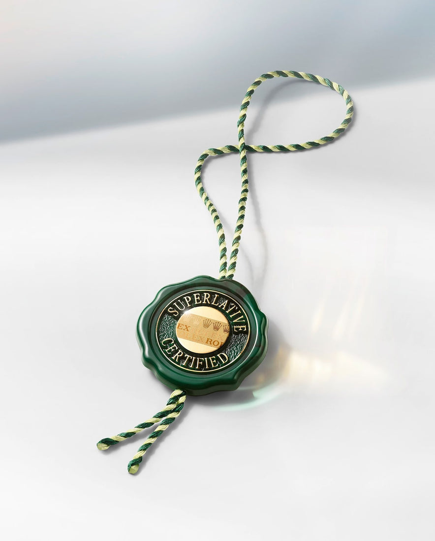 Green wax seal with SUPERLATIVE CERTIFIED text and gold embossed center, attached to twisted green and cream colored cord against a white surface.