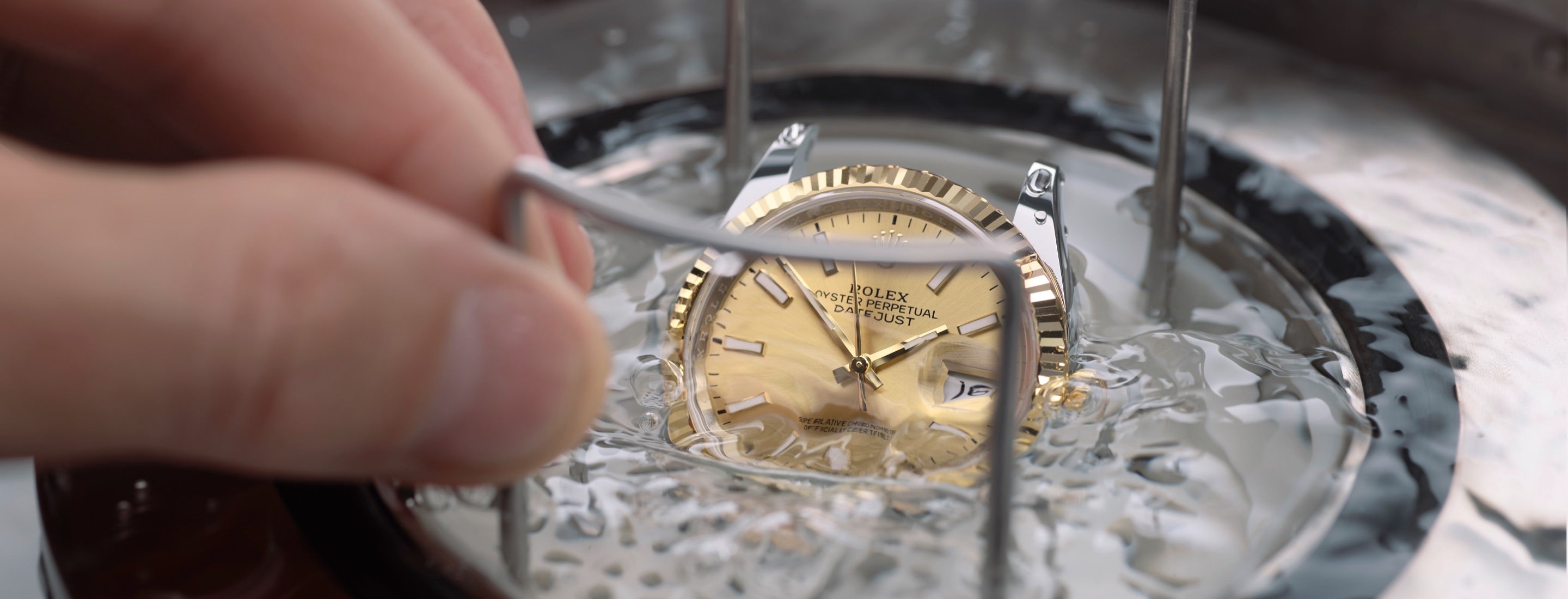 The image depicts a water-resistance test as part of Rolex's servicing procedure. It shows a watch being tested with a specialized device called a fathometer to ensure the watch’s seal integrity and water resistance are maintained.