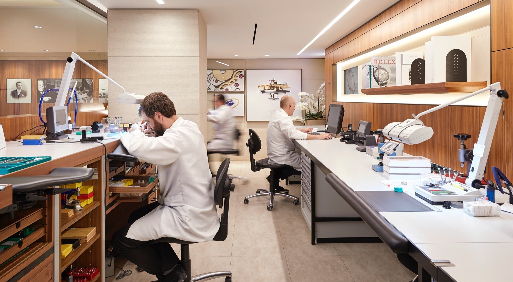 A Rolex service technician carefully inspecting a luxury Rolex watch under bright lighting in a professional service center.